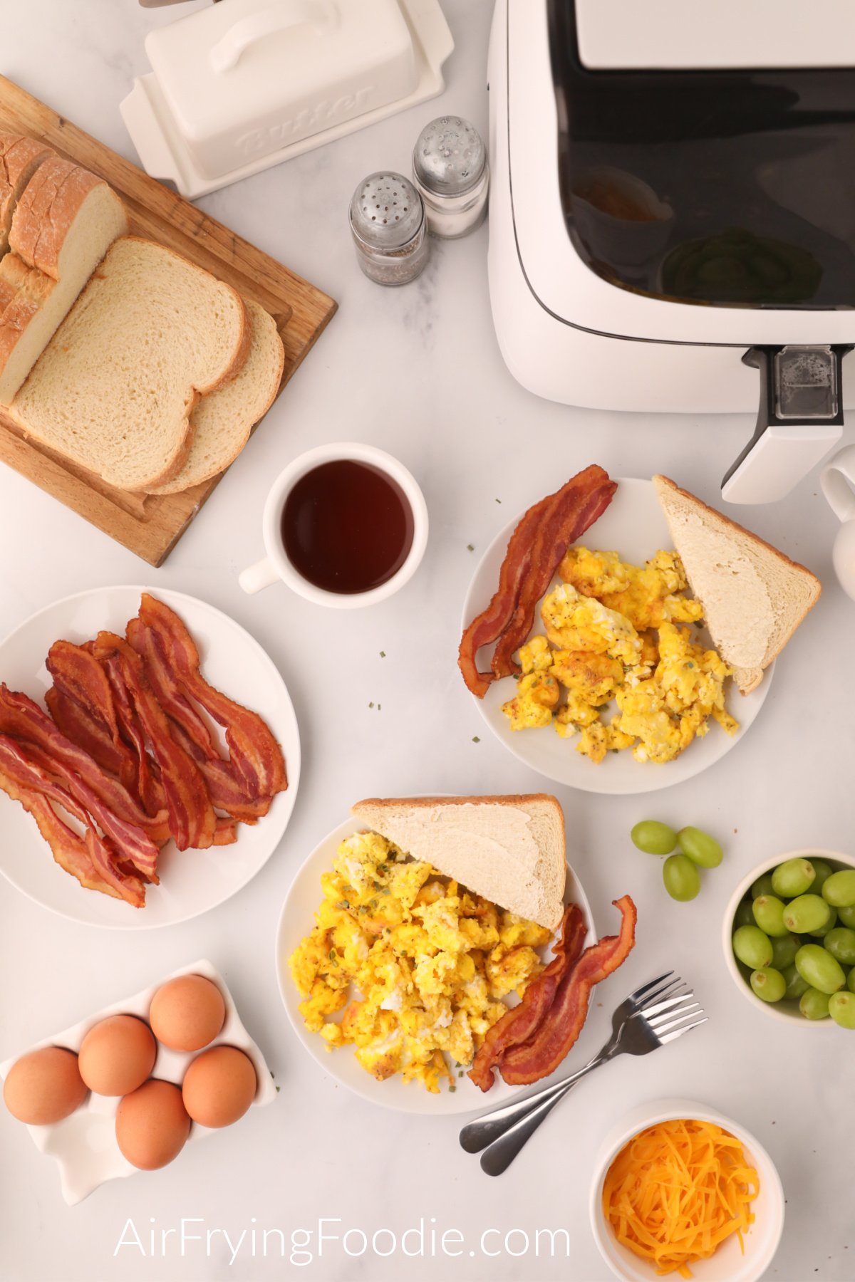 Breakfast plates with bacon and toast and scrambled eggs made in the air fryer, ready to serve.