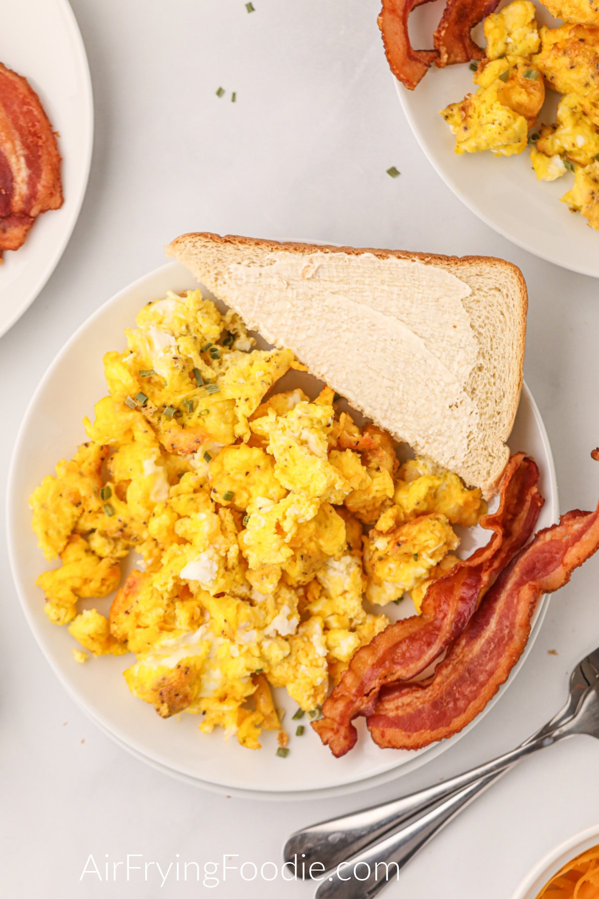 Air Fryer Scrambled eggs on a plate with toast and bacon and ready to eat.