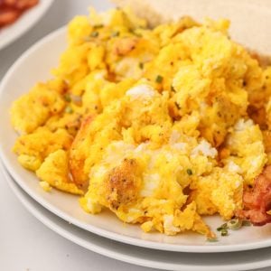 Scrambled eggs made in the air fryer on a white plate ready to serve.