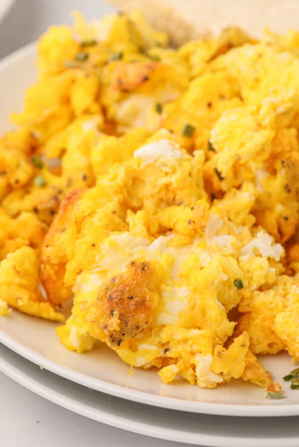 Scrambled eggs made in the air fryer on a white plate ready to serve.