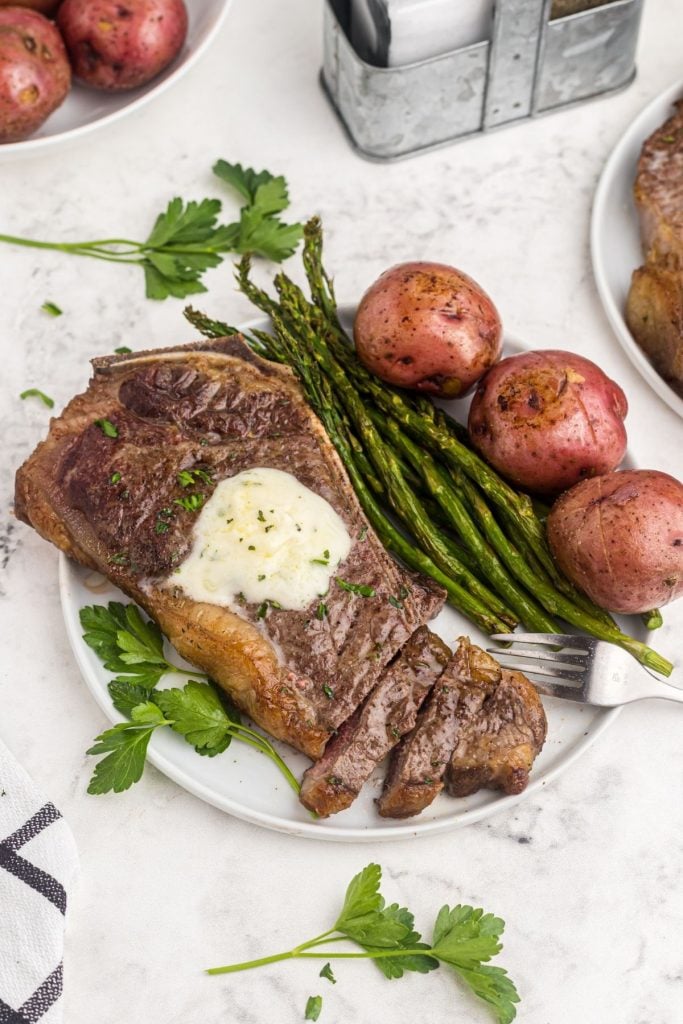 Cooked steak with asparagus and potatoes on a white plate. 