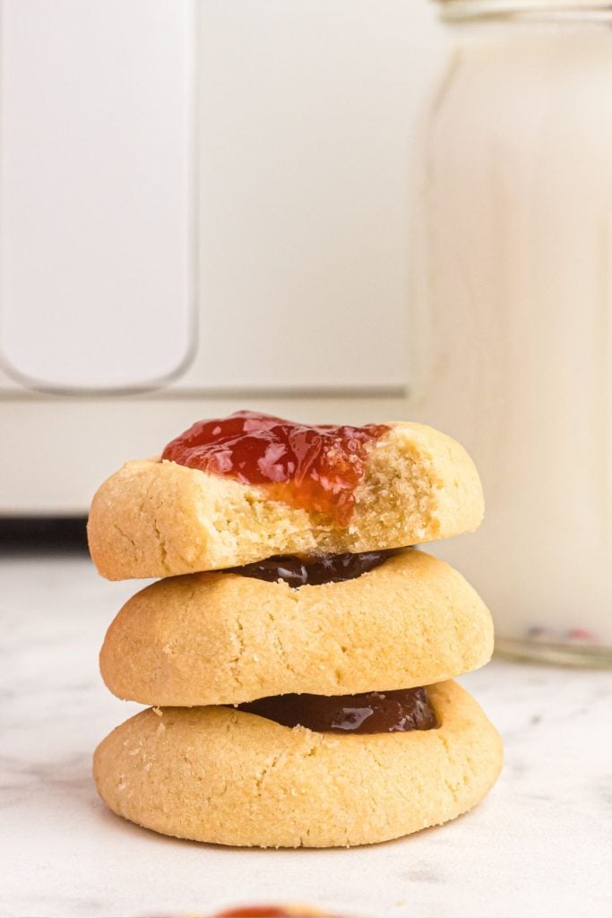 Three cookies stacked on a white marble table in front of the air fryer