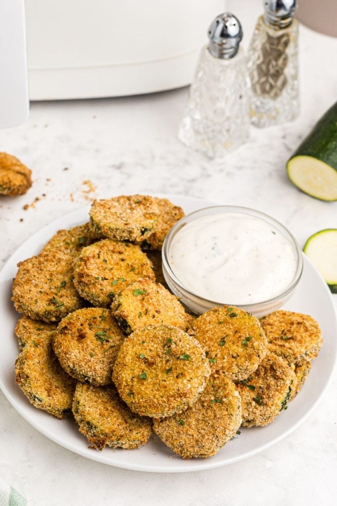 Crispy breaded zucchini chips after being cooked in the air fryer with ranch dressing dip