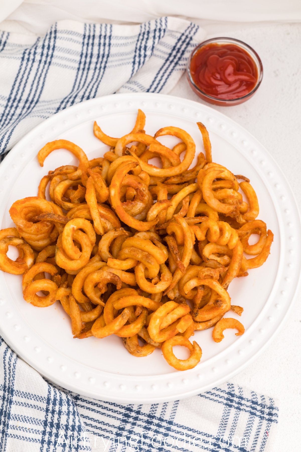 air fried curly fries on a white plate ready to eat. 