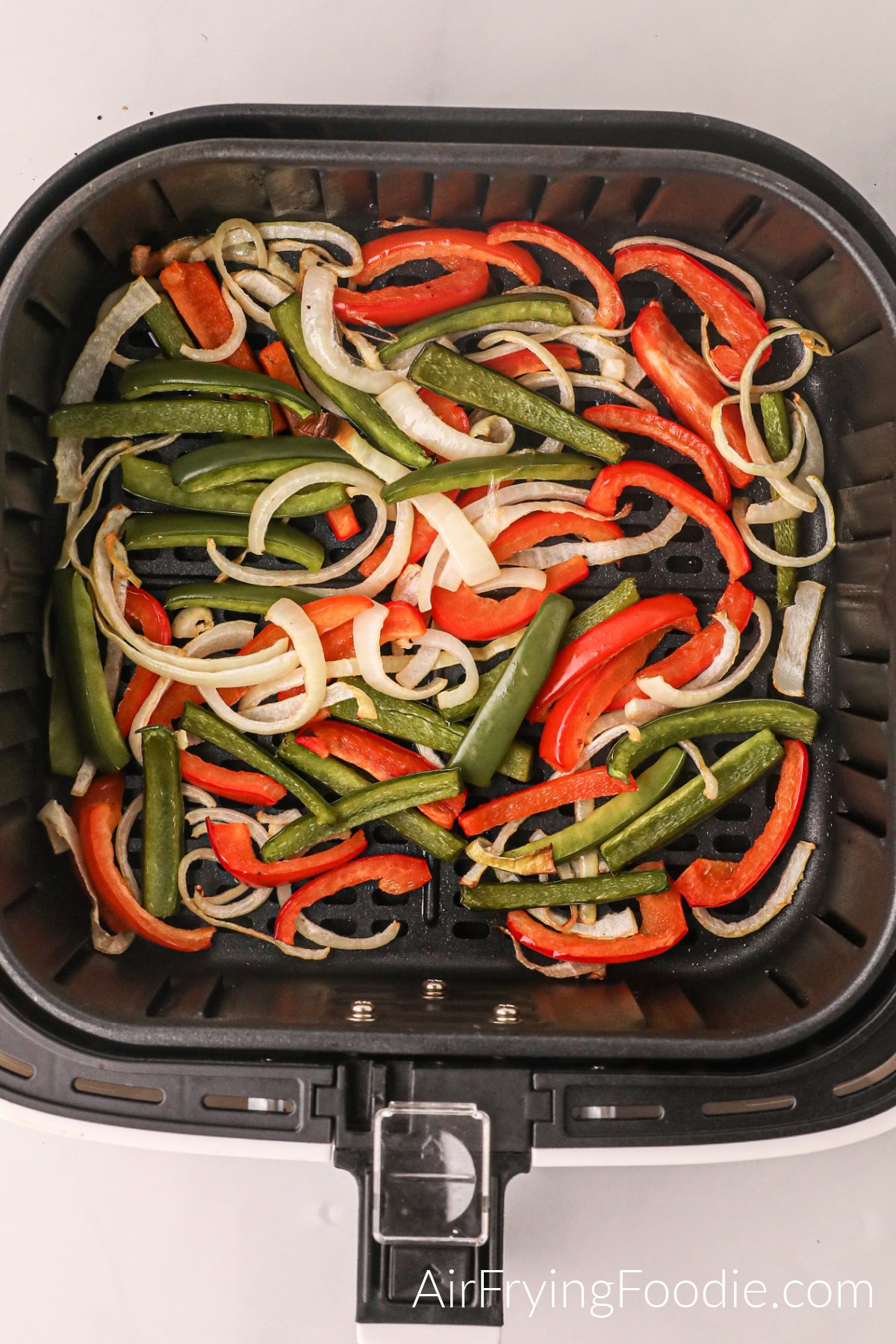 Peppers and onions in the basket of the air fryer.