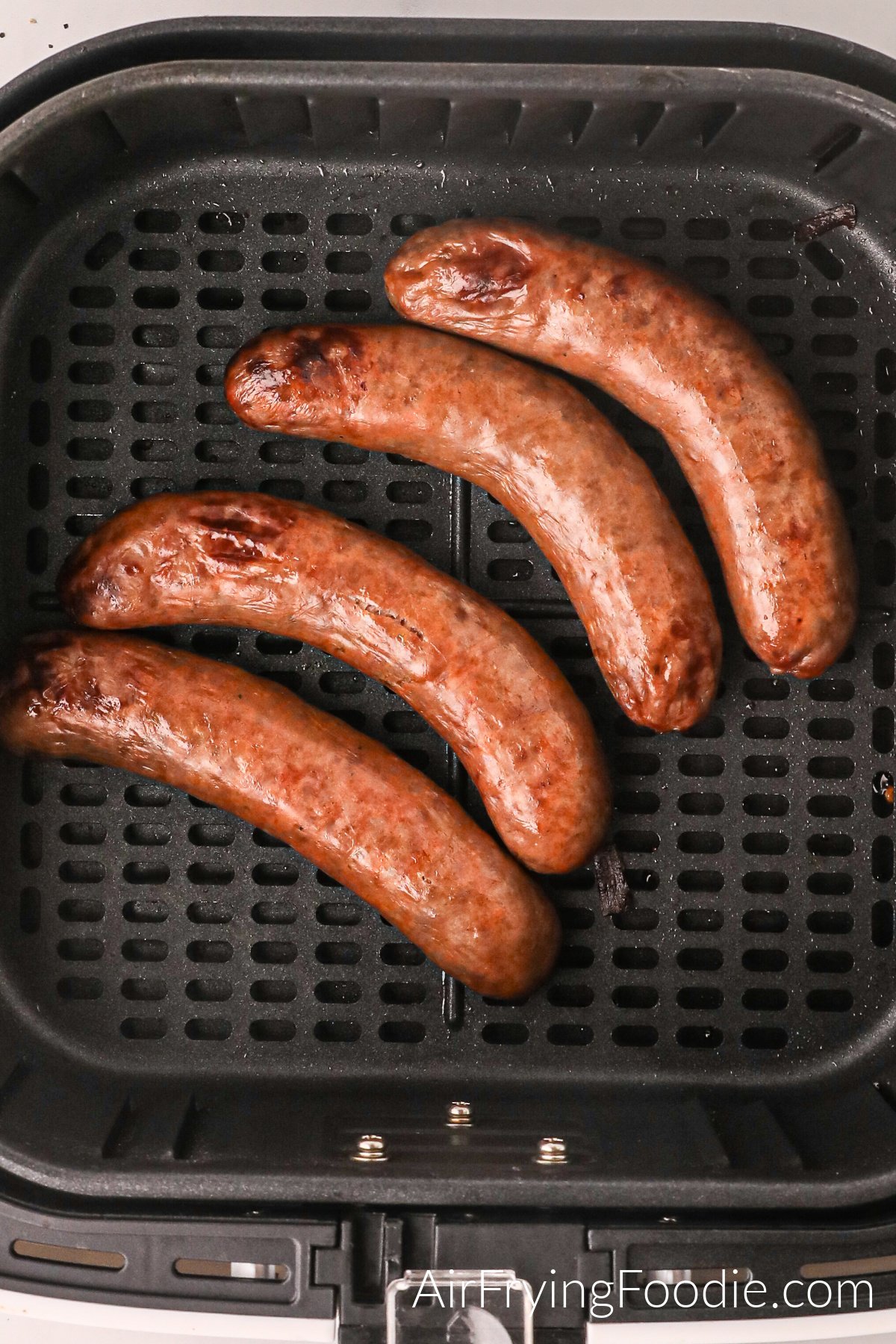 Fully cooked Italian sausages in the basket of the air fryer.