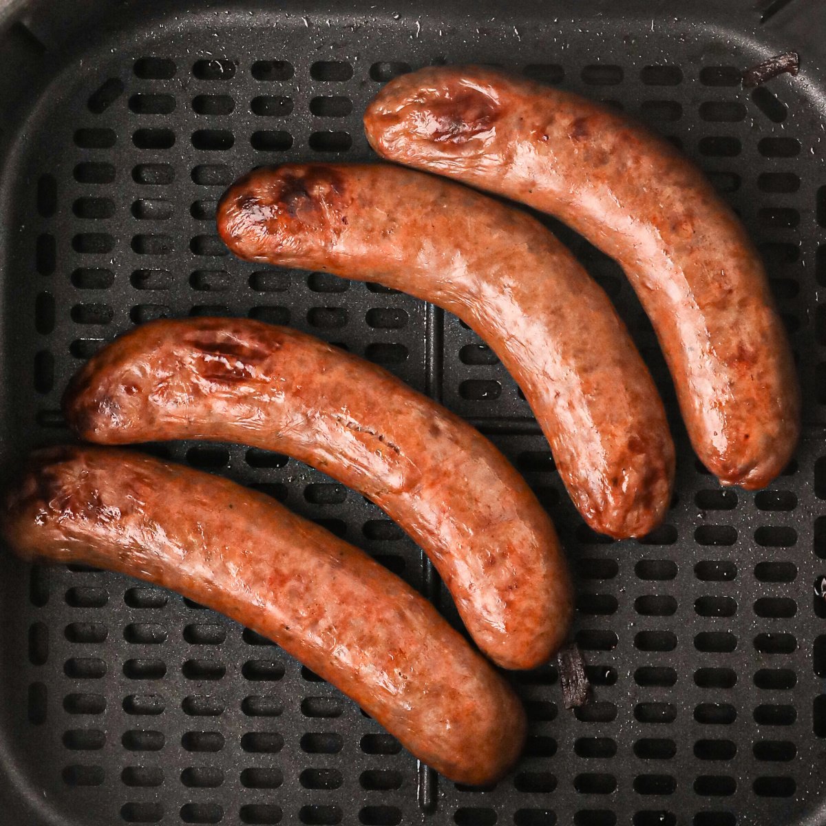 Italian Sausage in air fryer basket ready to eat.