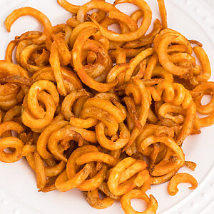 air fried frozen curly fries on a white plate, ready to eat.