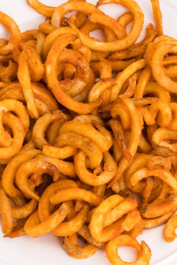 air fried frozen curly fries on a white plate, ready to eat.