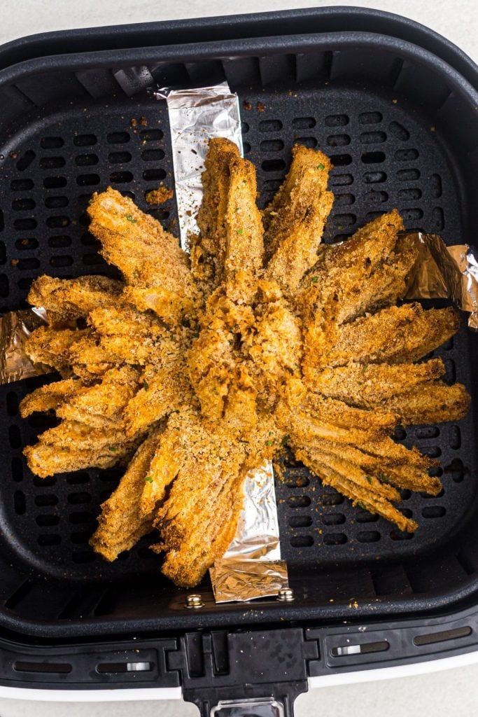 Golden crispy bloomed onion in the air fryer basket after being cooked