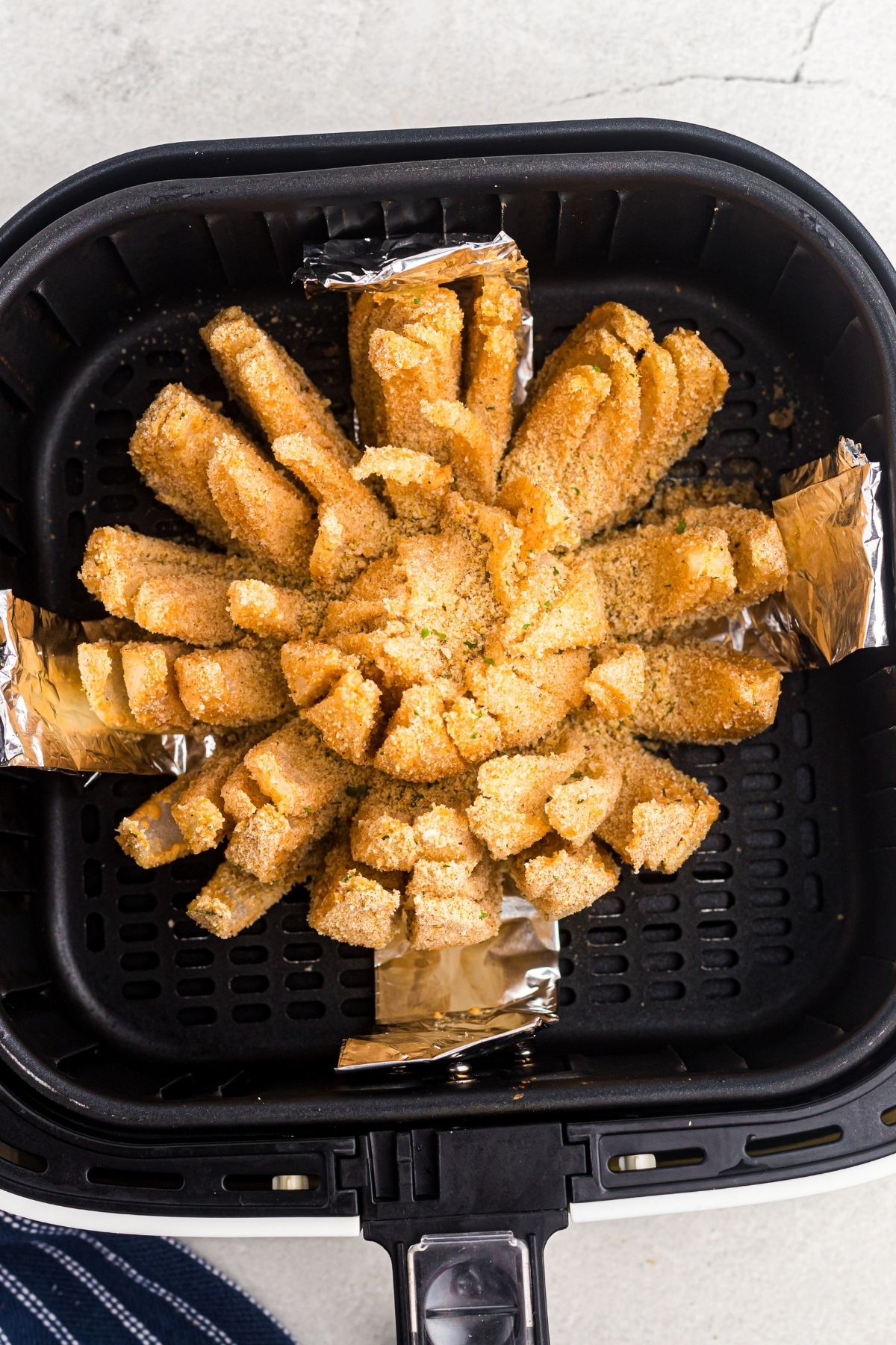 Golden battered and coated bloomed open sliced onion in the air fryer basket