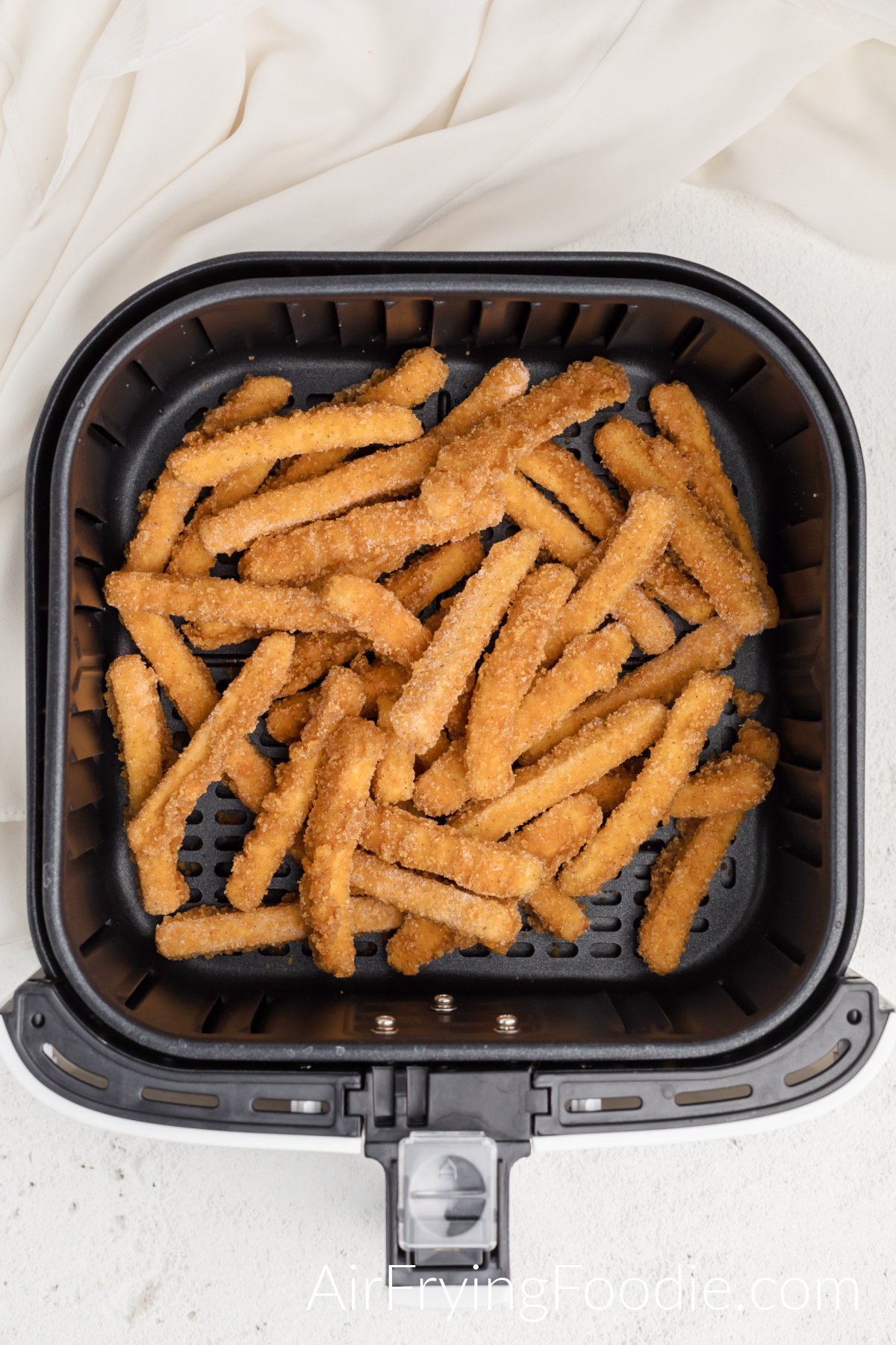 Frozen chicken fries in air fryer basket, ready to cook.