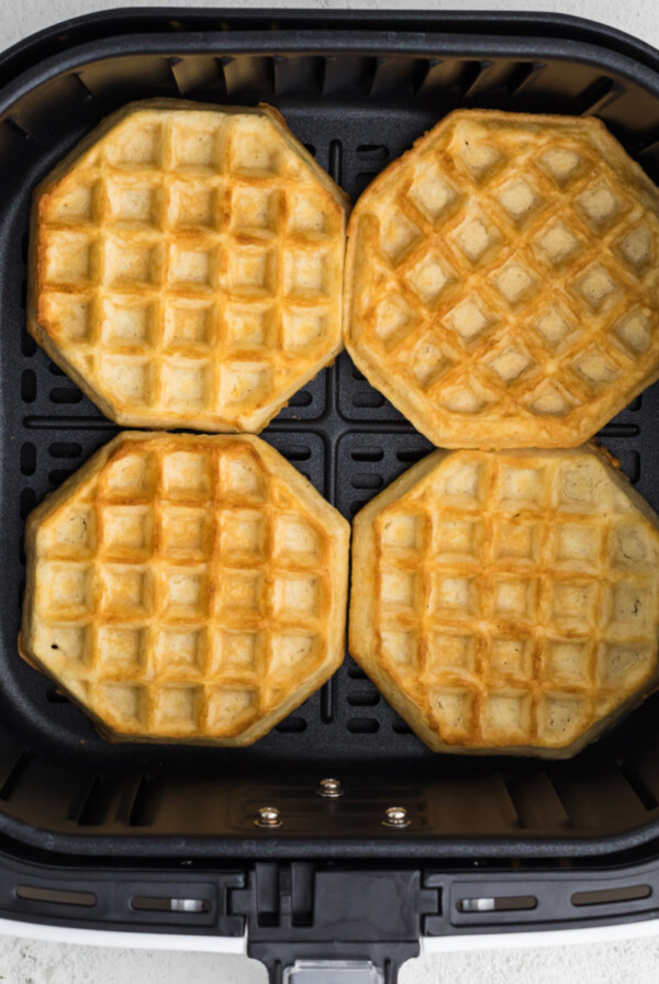 Fully cooked frozen waffles in air fryer basket in a single layer.