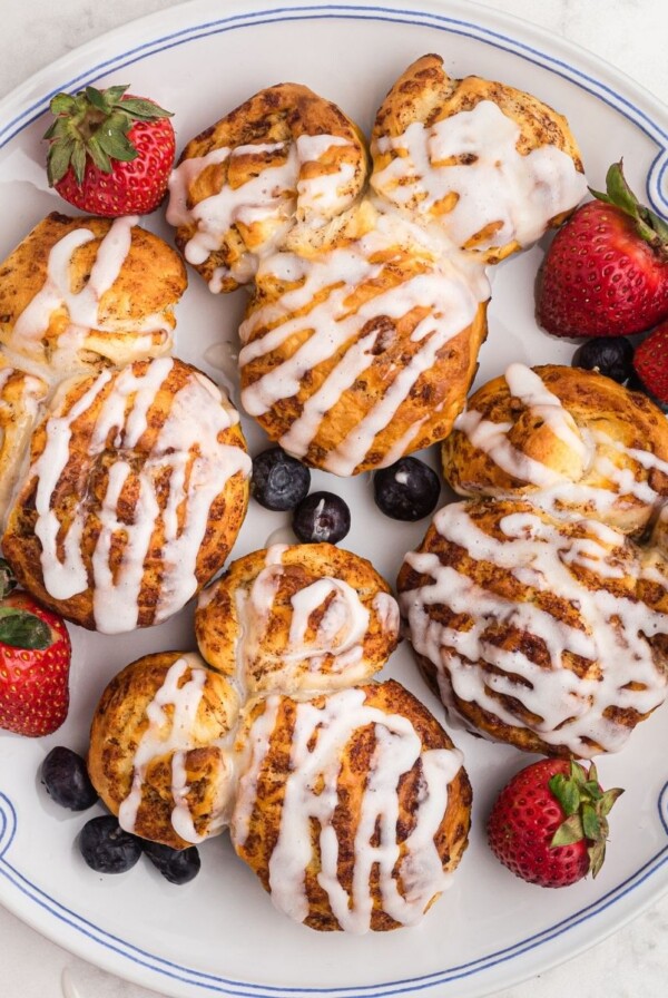 Mickey shape cinnamon rolls on a white plate with berries on a marble table