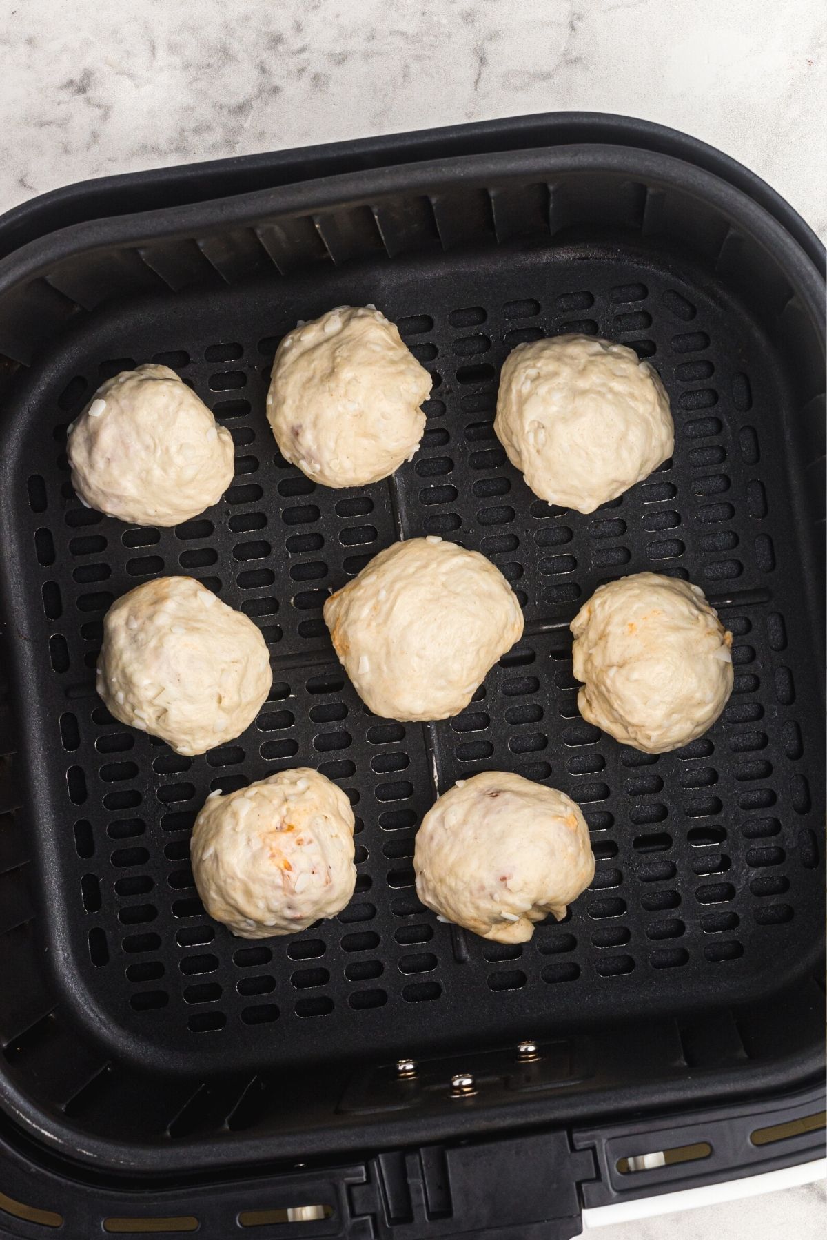 Biscuits filled with pizza toppings, wrapped into balls placed in the air fryer basket
