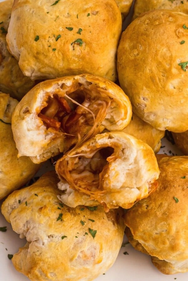 Golden biscuits filled with pizza toppings stacked on a white plate