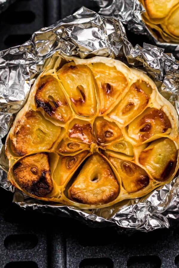 Golden roasted garlic on a piece of foil in the air fryer basket.