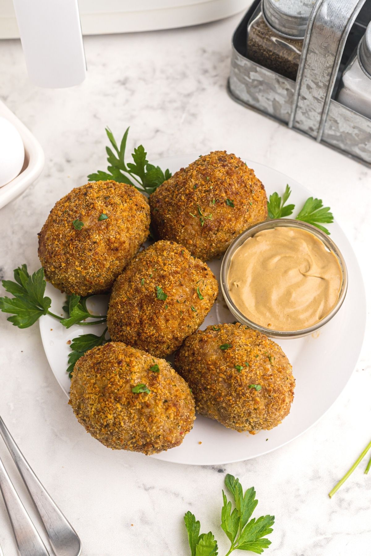 Air fried Scotch eggs on a white plate garnished with parsley.