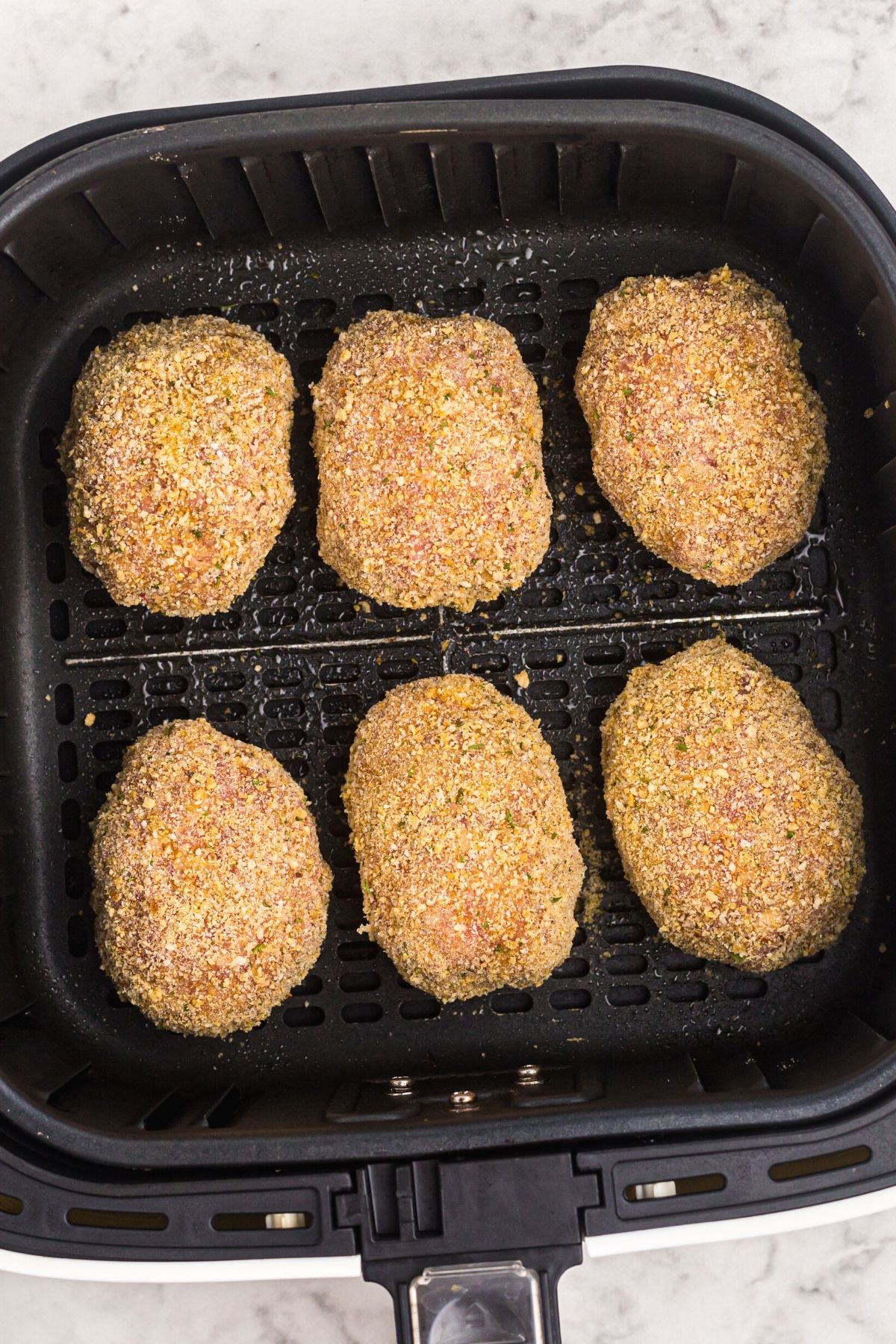 Bread coated eggs in the air fryer basket before being cooked