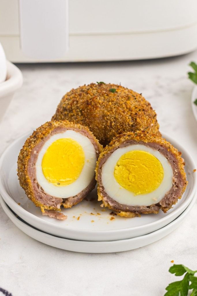 close up photo of scotch egg cut open showing hard boiled egg coated with pork sausage and crumbs