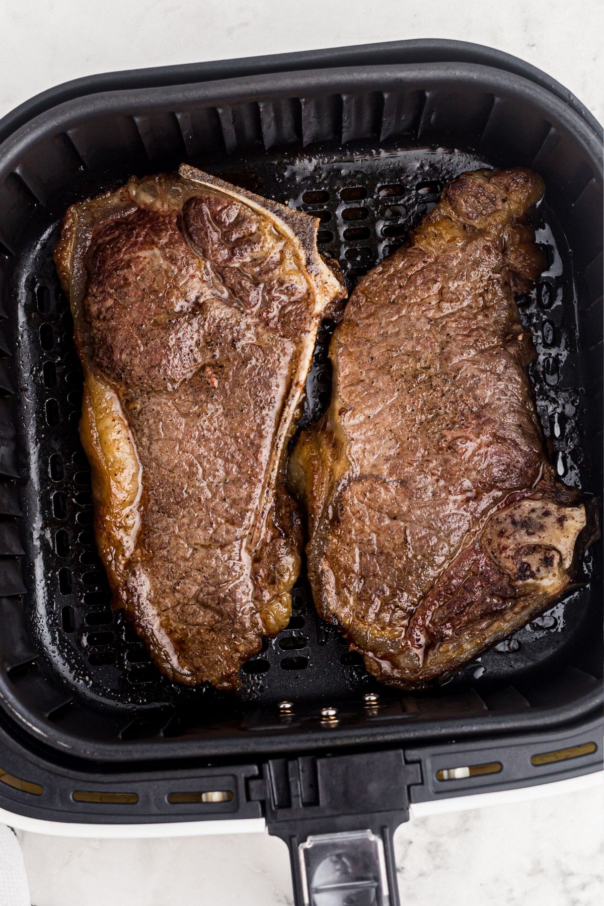 Juicy cooked steaks in the air fryer basket after being cooked