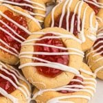 Golden cookies topped with seedless jam and drizzled with white chocolate