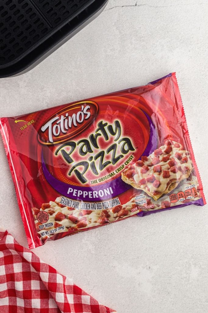 Packaged tostino's party pizza on a white counter with an air fryer basket