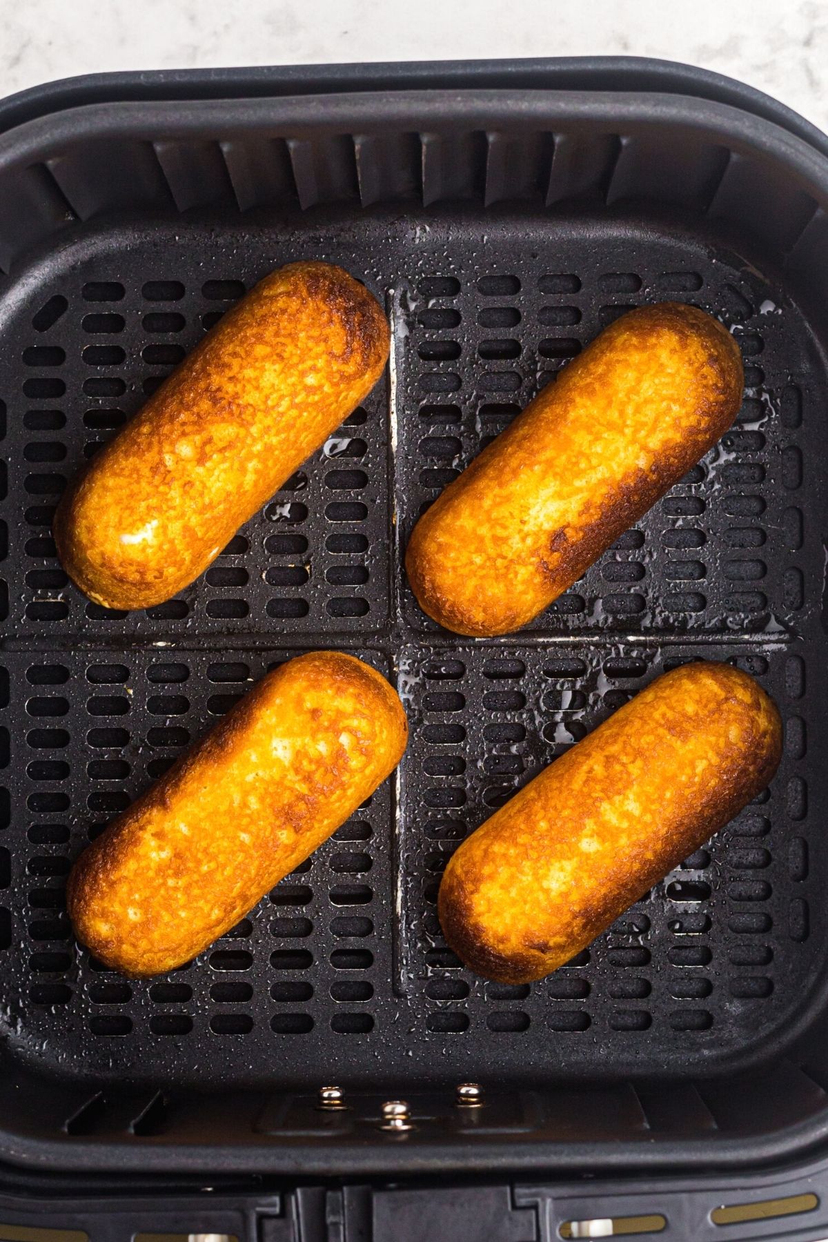 Golden crispy twinkies in the air fryer basket after being cooked