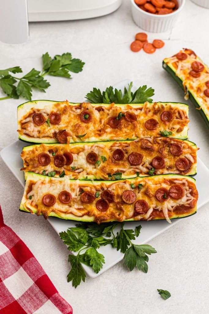 Golden cheese and pepperonis on slices of zucchini cooked and served on a white plate