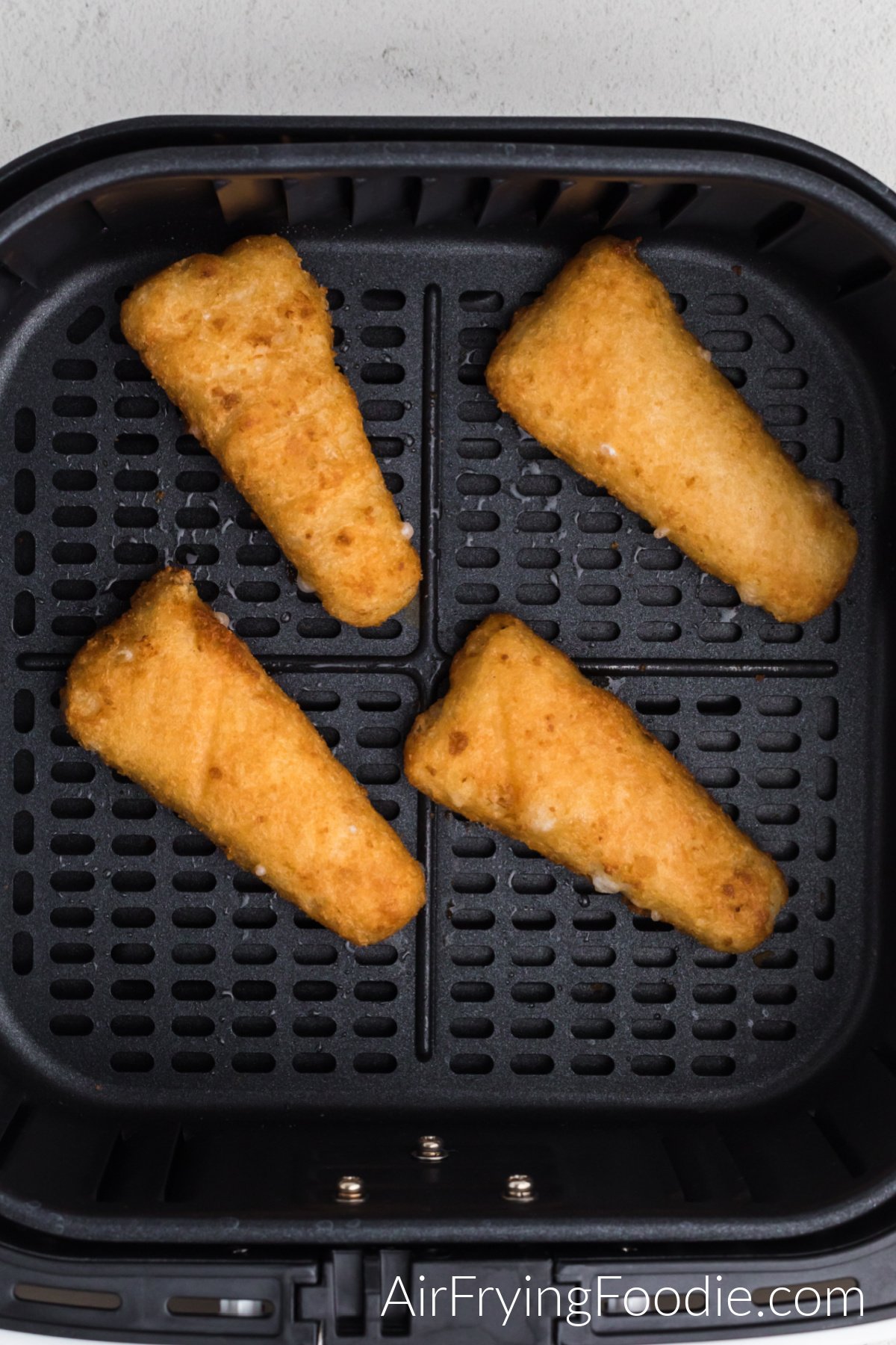 Fully cooked fish fillets in the basket of the air fryer.