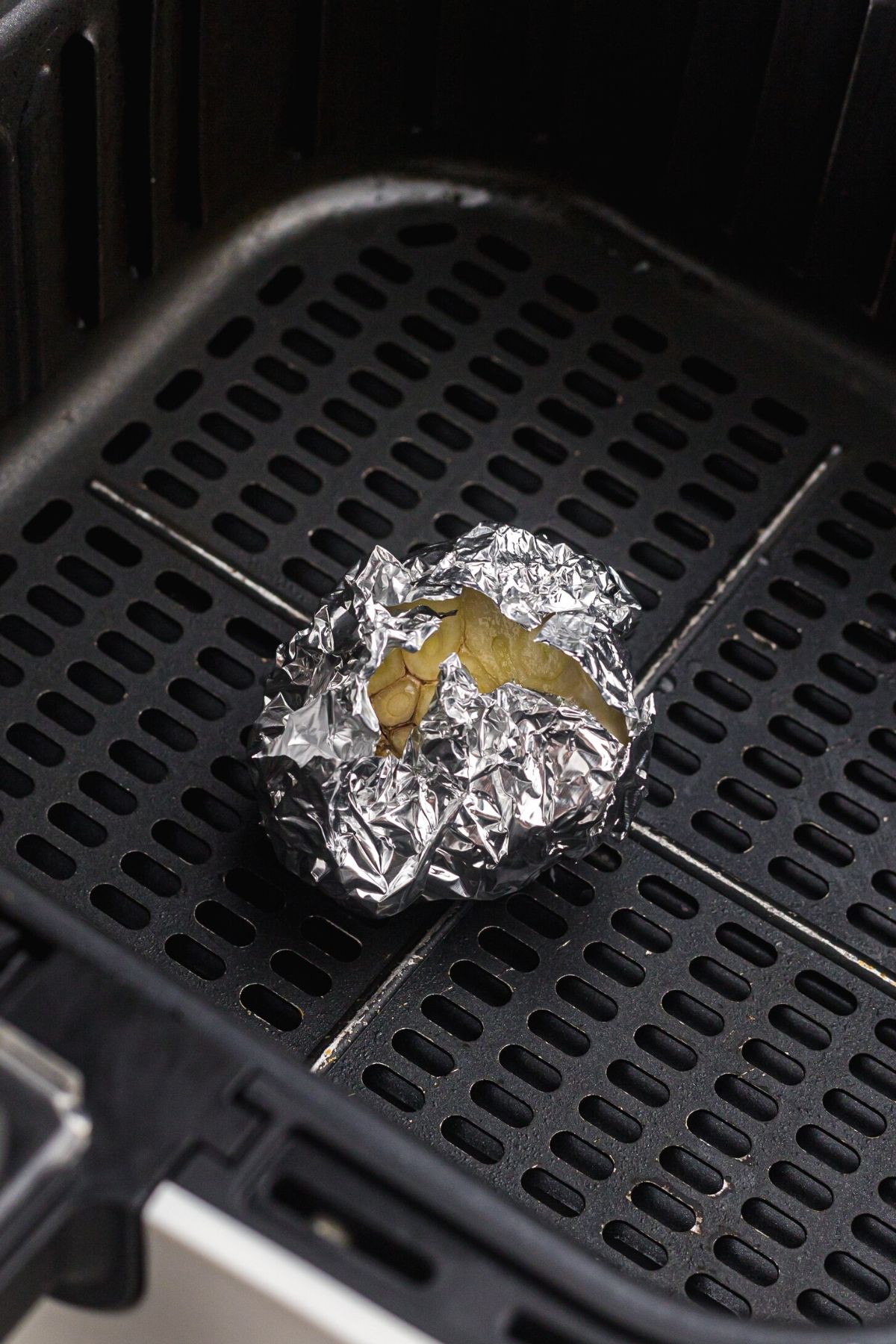 Bulb of garlic wrapped in foil in the air fryer basket