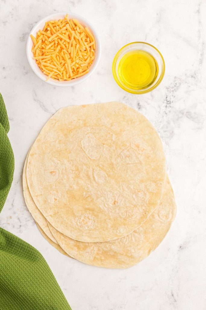 Ingredients needed to make quesadillas of tortillas, olive oil, and cheese.
