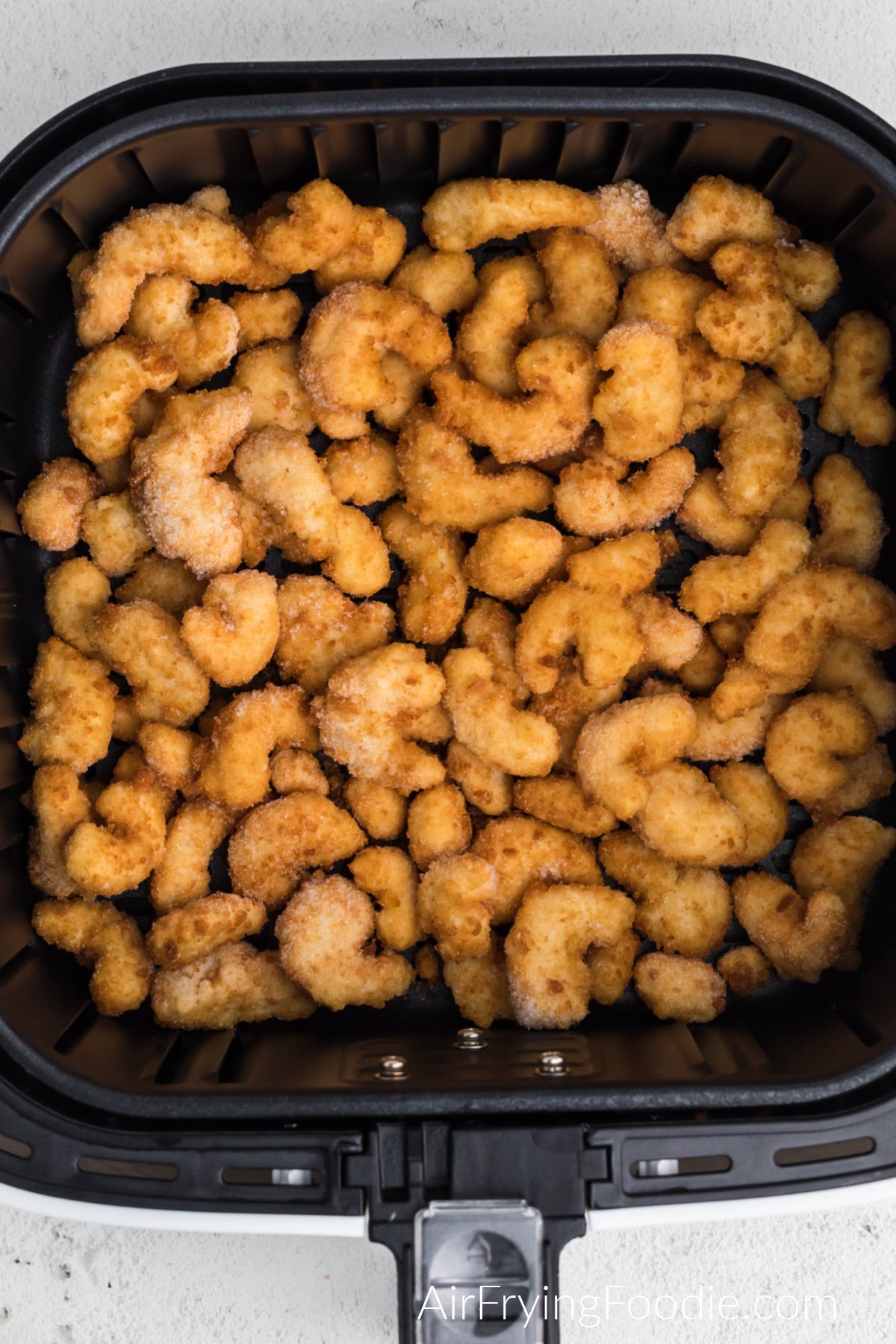 Frozen popcorn shrimp in air fryer basket, ready to be air fried.