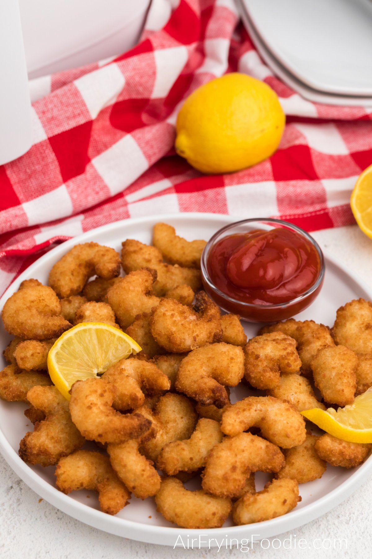 Frozen popcorn shrimp air fried to a crispy golden brown and served on a plate. 