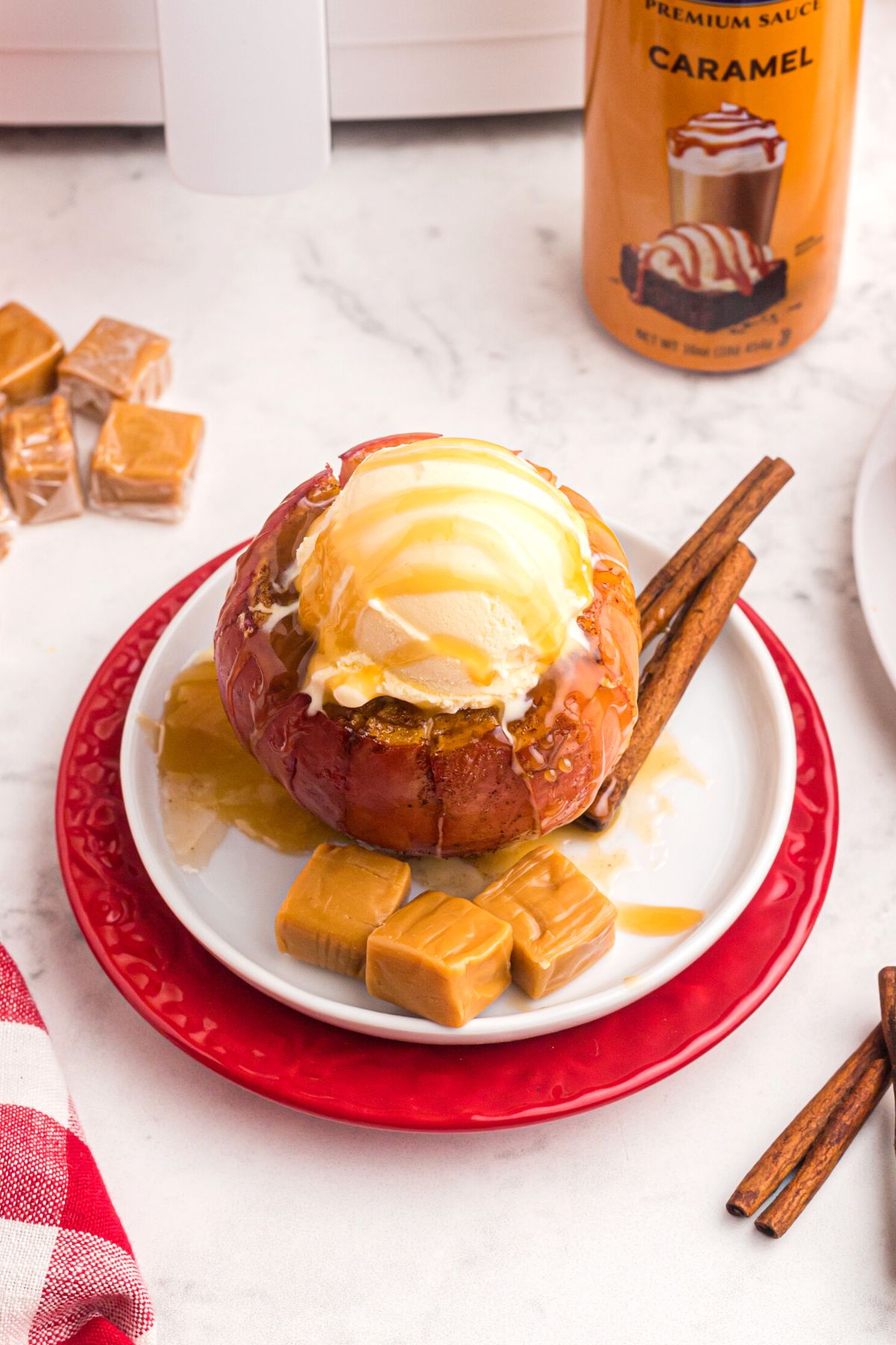 Bloomin' Apple on a plate with a scoop of ice cream, caramels, and cinnamon sticks. 