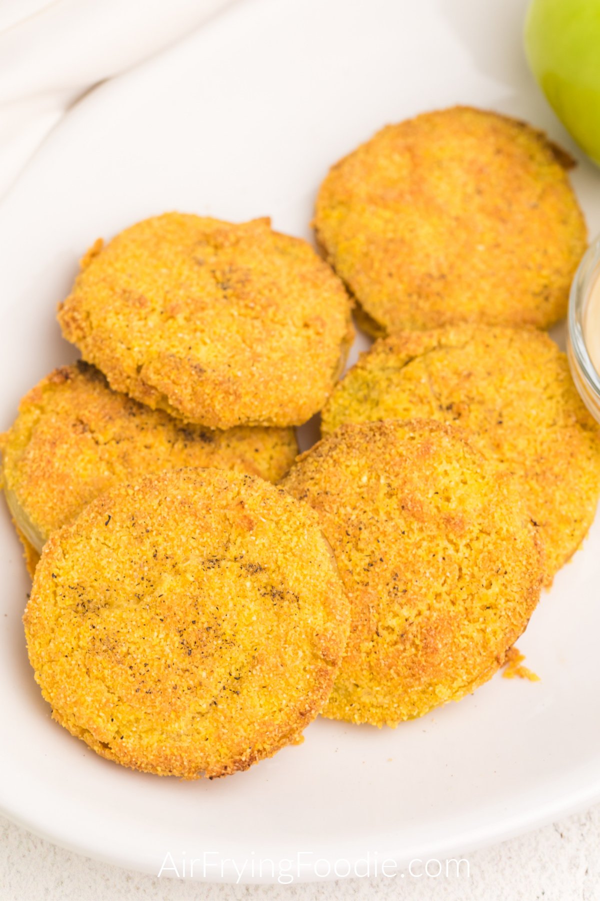 Close up photo of air fryer fried green tomatoes on a white plate with dipping sauce, ready to be served. 