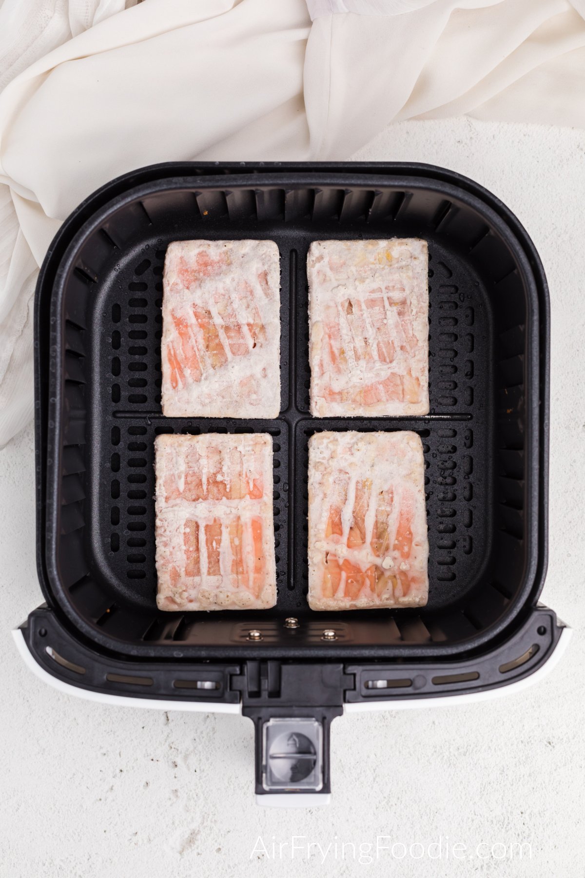 frozen salmon in air fryer basket, ready to cook.