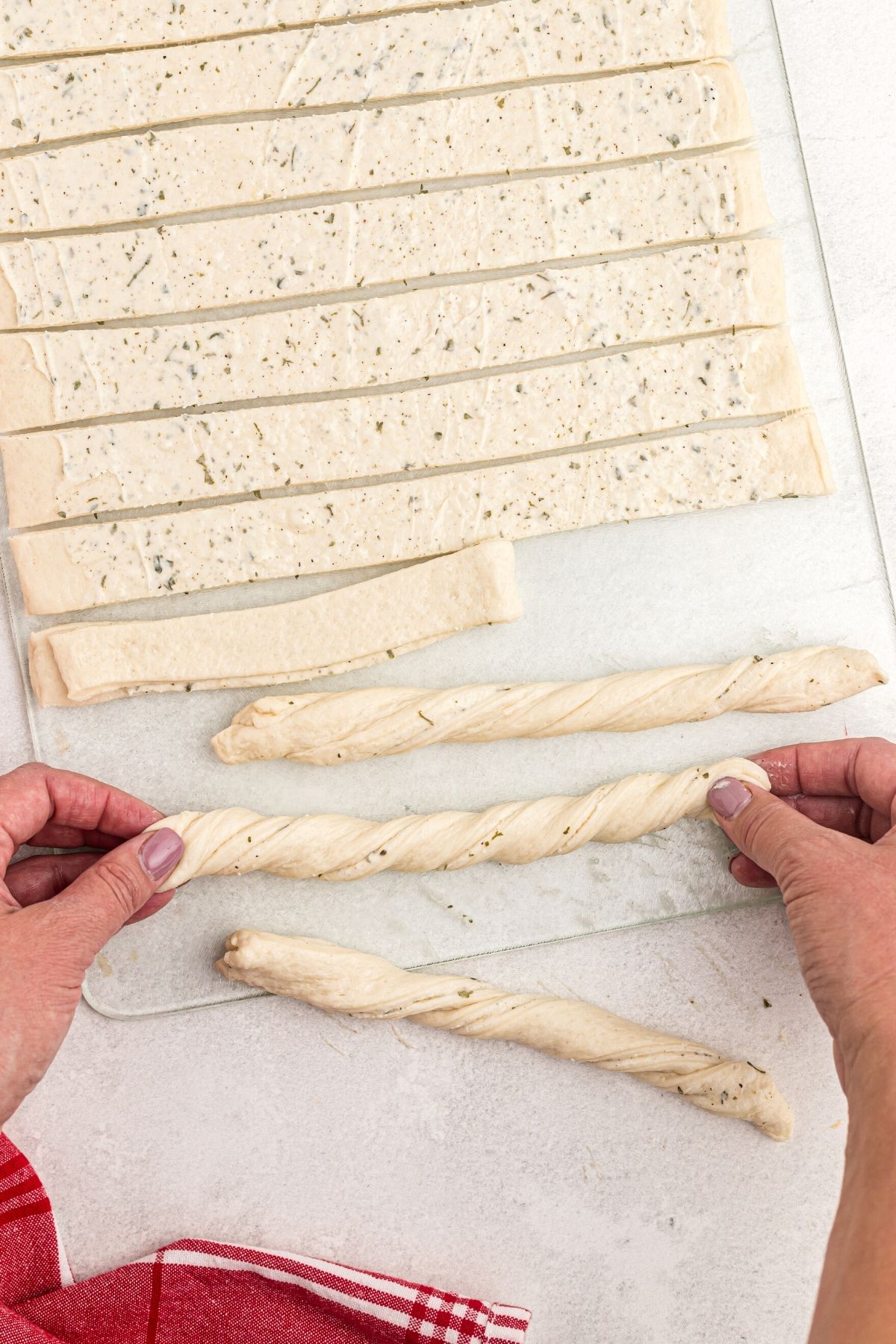 Strips of sough being rolled into breadsticks and twisted