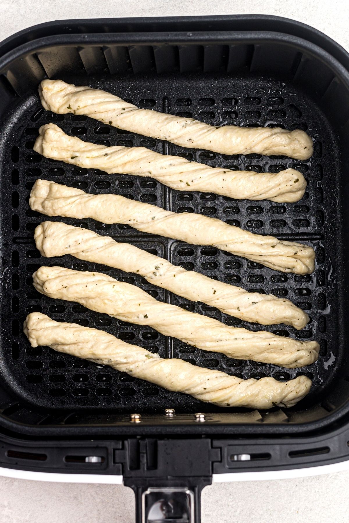 raw breadstick dough rolled and twisted in the air fryer basket