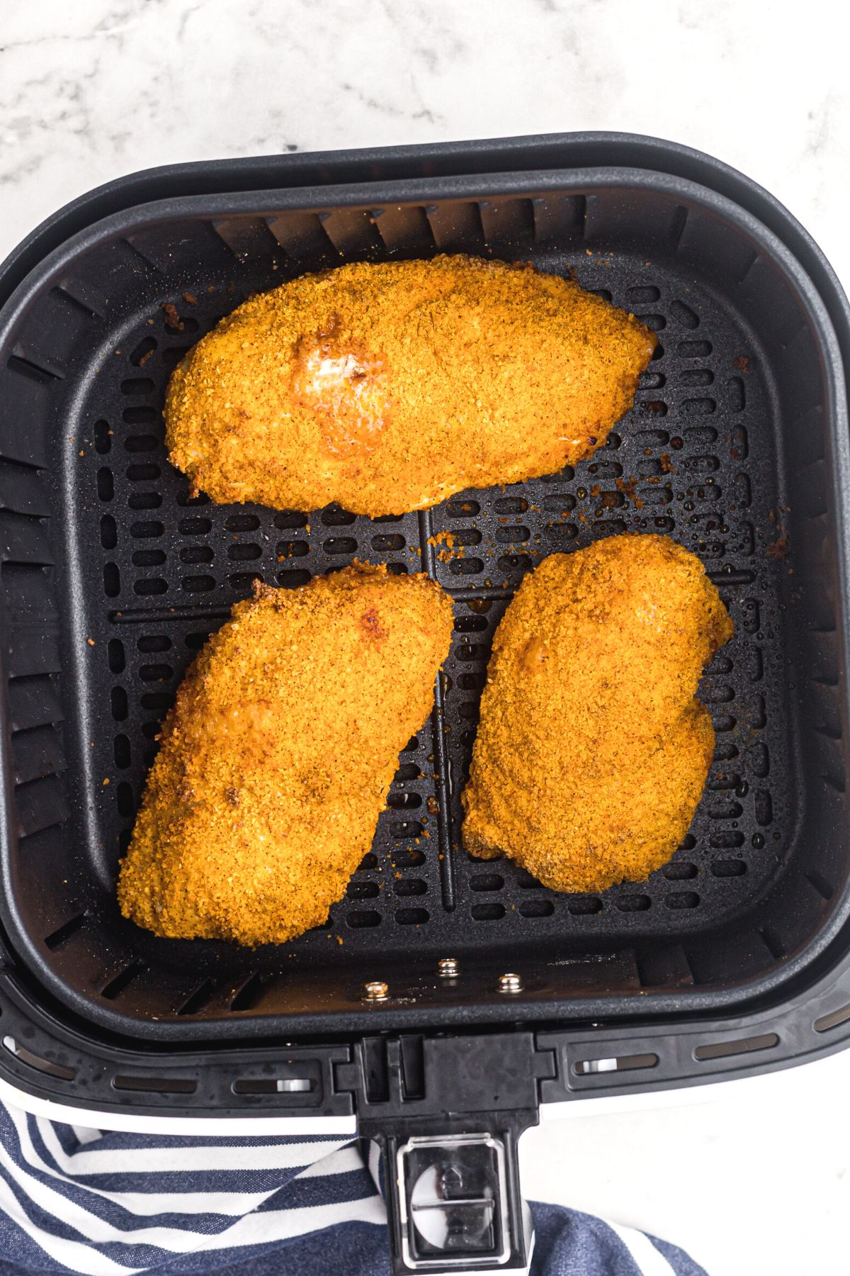 Crispy chicken coated with seasonings in the air fryer basket after being cooked