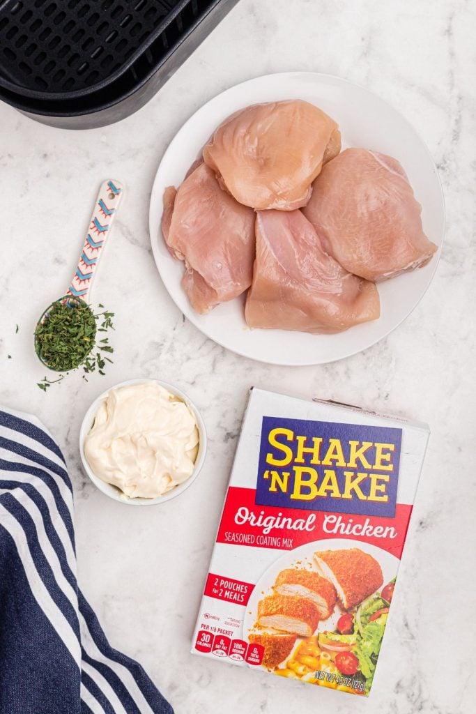 Ingredients needed to make shake and bake chicken on a white marble table