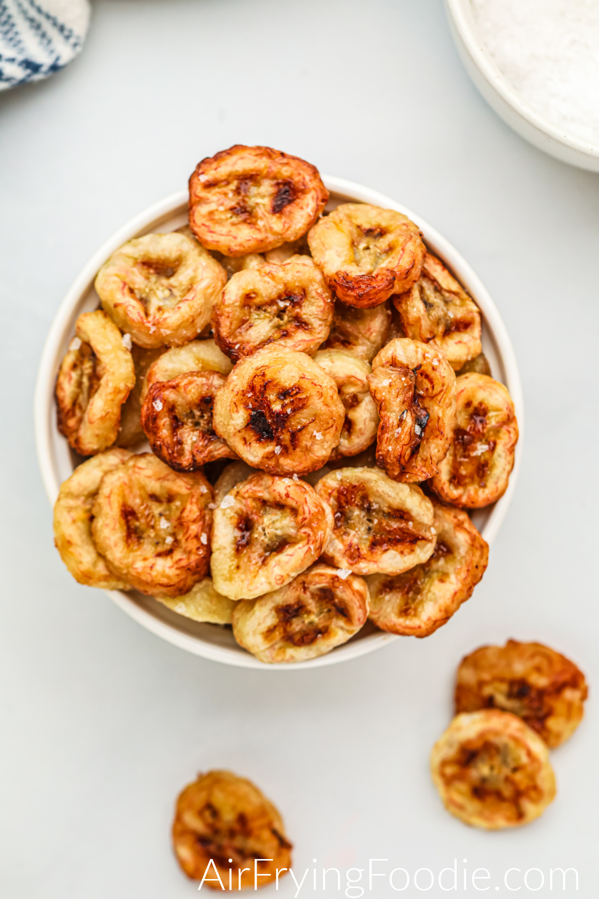 Air fried banana chips in a bowl with salt sprinkled on them, ready to serve. 