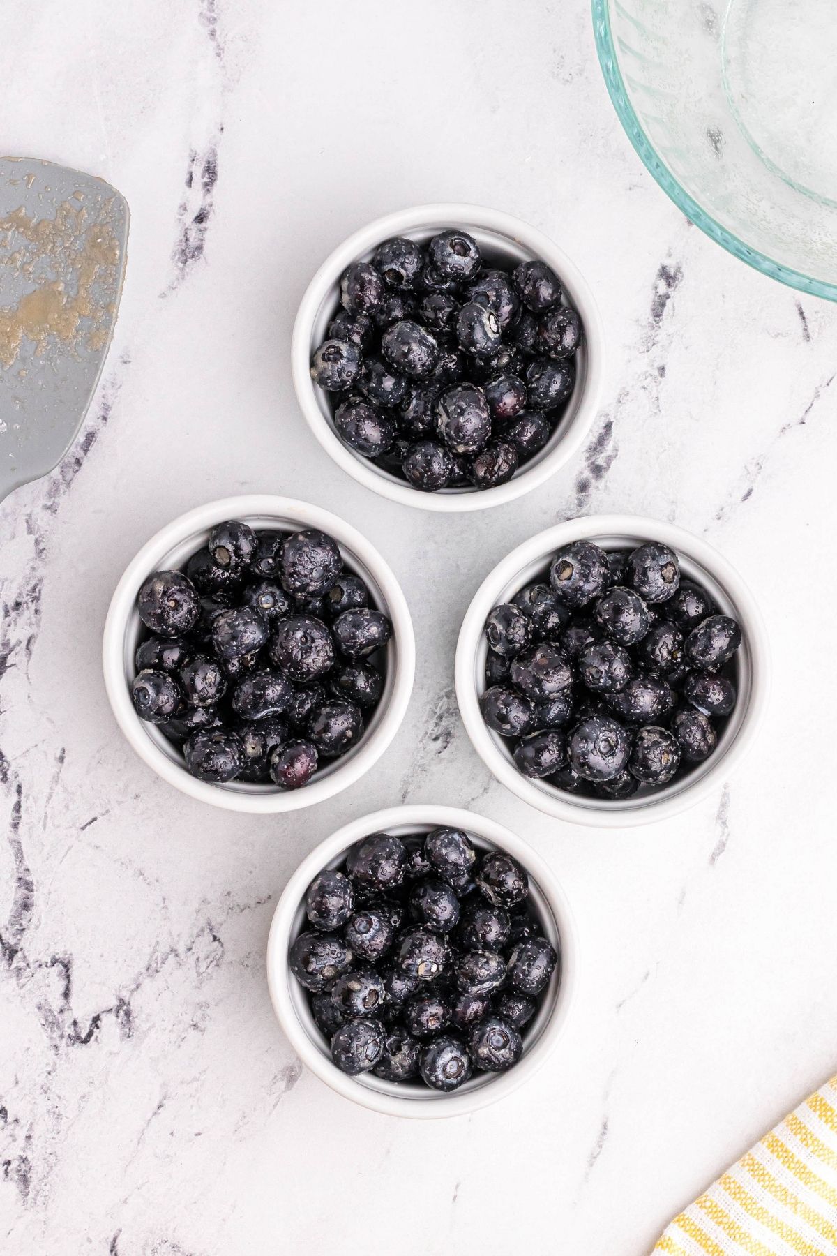 Four white ramekins filled with blueberries