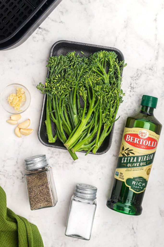 Ingredients needed to make broccolini in the air fryer on a white marble table
