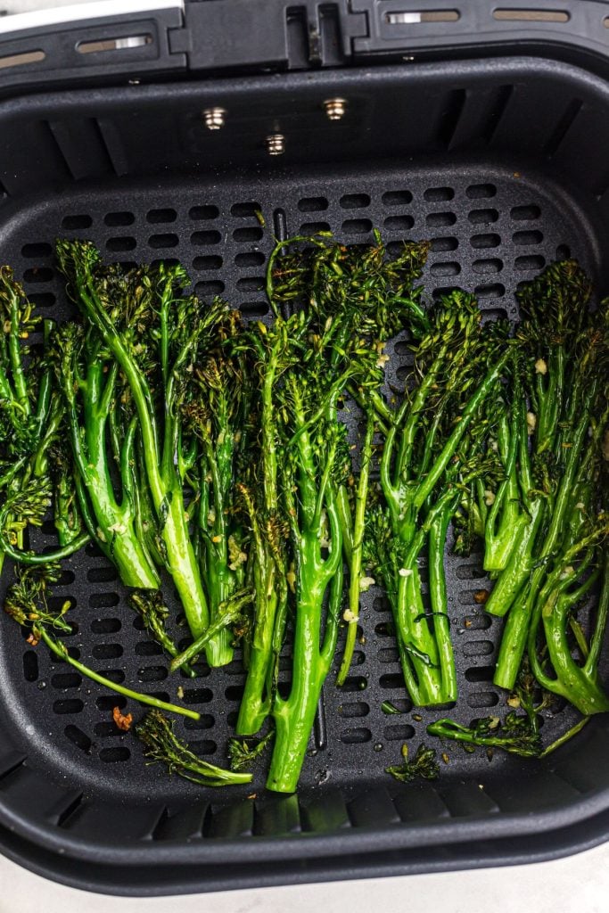 Juicy lightly crisped broccolini florets in an air fryer basket