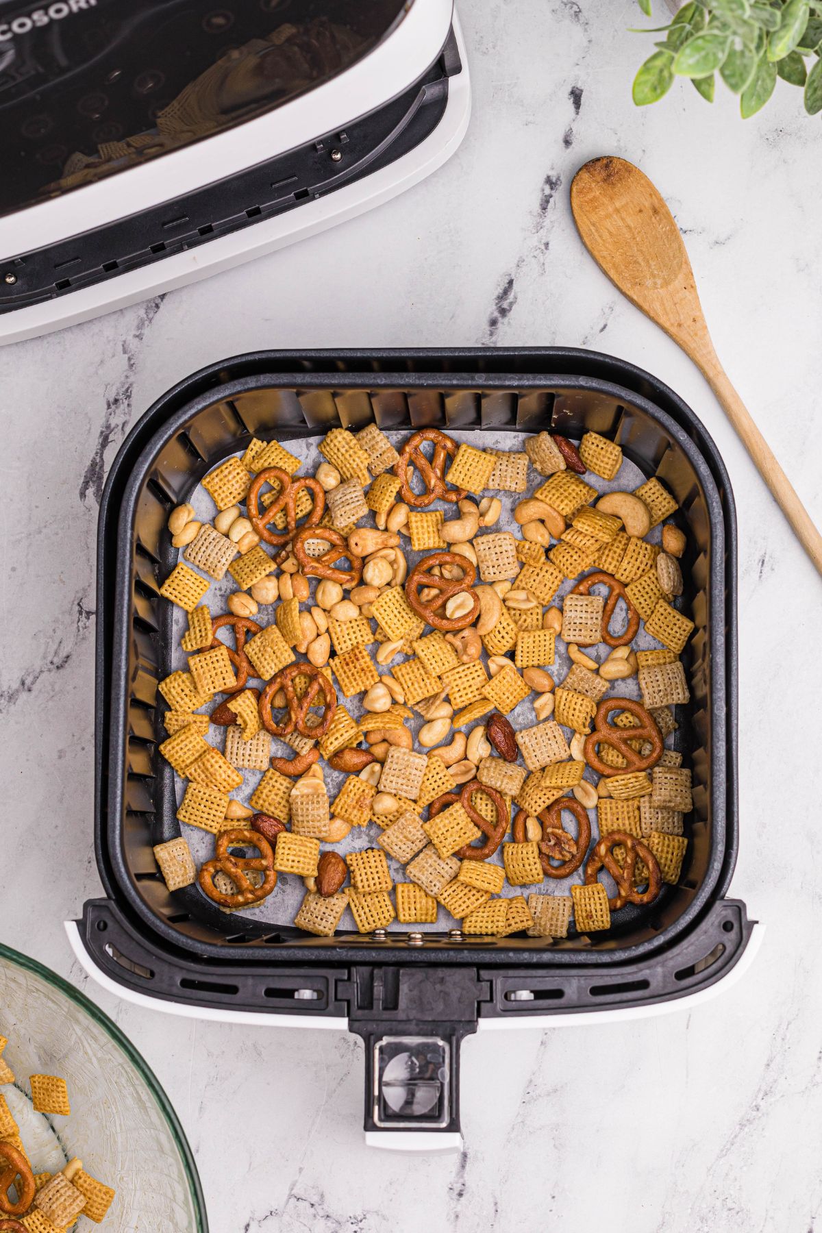 Air fryer chex mix being added to the basket before being cooked