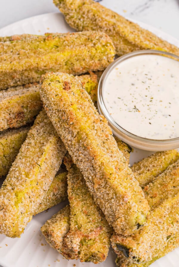 Overhead photo of crispy air fried dill pickles on a white plate with dipping sauce.