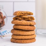 Stacked gingersnap cookies in front of milk and cinnamon sticks