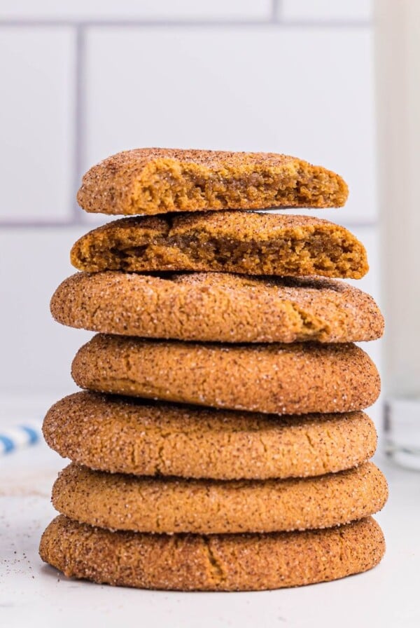 Stacked gingersnap cookies in front of milk and cinnamon sticks