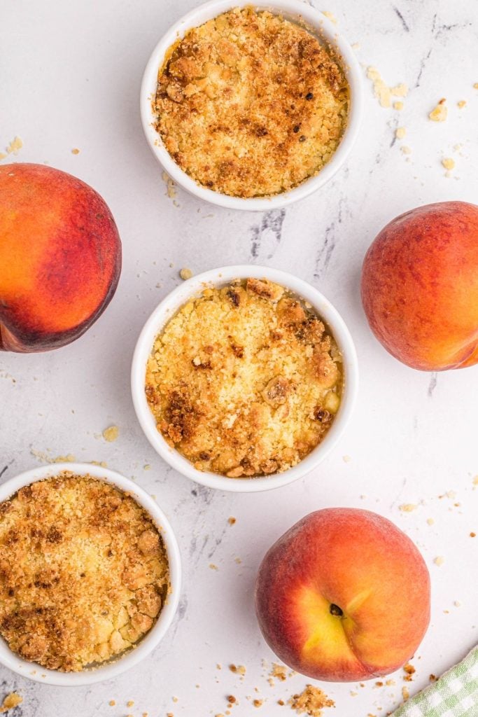 Golden peach crisps on a white marble board with fresh peaches 